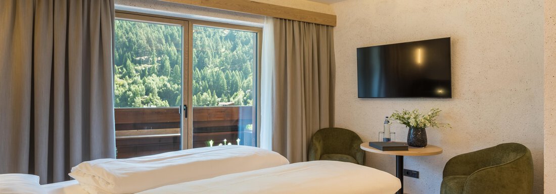 Ein modernes Hotelzimmer mit zwei Betten und einem Fernseher. Große Fenster bieten einen Blick auf die Natur. - Hotel Alpina - Sölden
