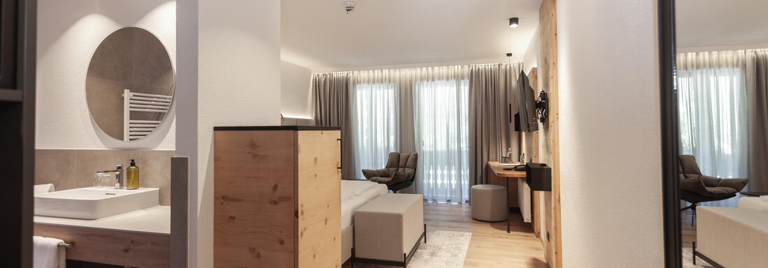 A modern designed room with a cozy seating area and plenty of natural light. The decor is bright and friendly, featuring wood and neutral tones. - Hotel Hubertus - Sölden