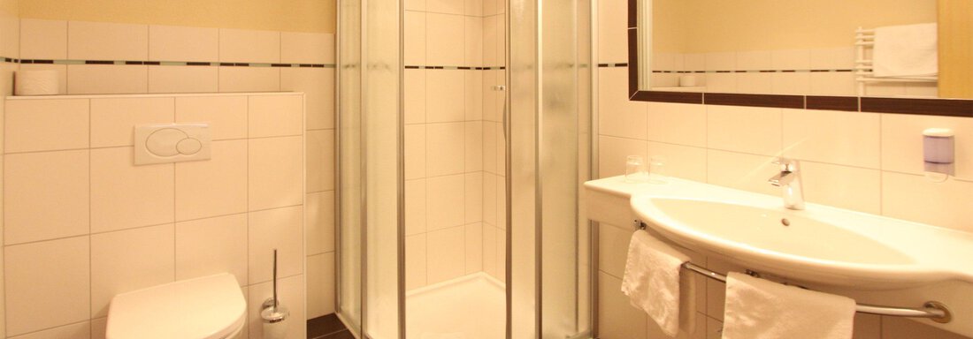 App1_Badezimmer Ein modernes Badezimmer mit einer Glasdusche und einem Waschbecken. Die Wände sind hell gefliest, und es gibt eine große Spiegeloberfläche. - Hotelappart Peter - Sölden
