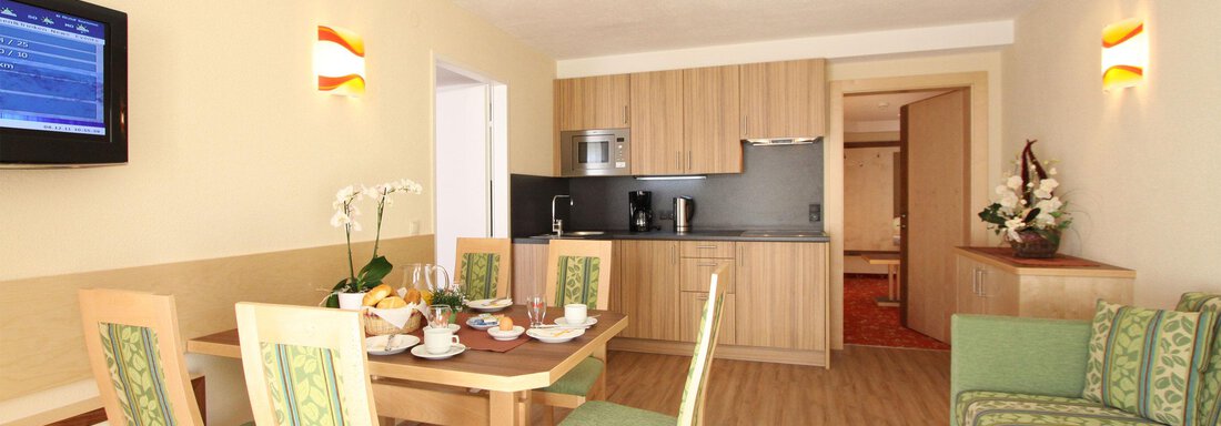 Ein modernes Wohnzimmer mit einer gemütlichen Sitzecke und einem Esstisch. Die Küche ist offen und gut ausgestattet, mit einer hellen und einladenden Atmosphäre. - Hotelappart Peter - Sölden