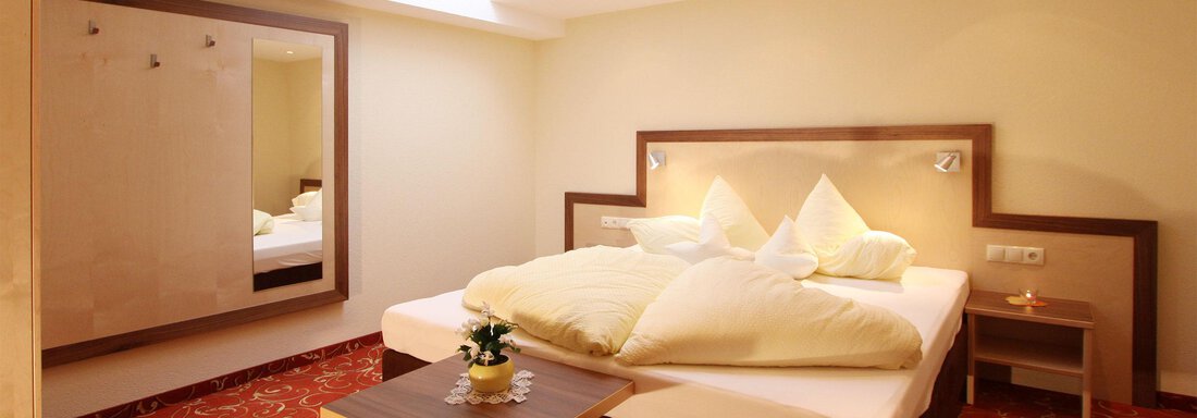 Ein modernes Schlafzimmer mit einem großen Bett und frischen Kissen. Die warmen Töne schaffen eine einladende Atmosphäre. - Hotelappart Peter - Sölden