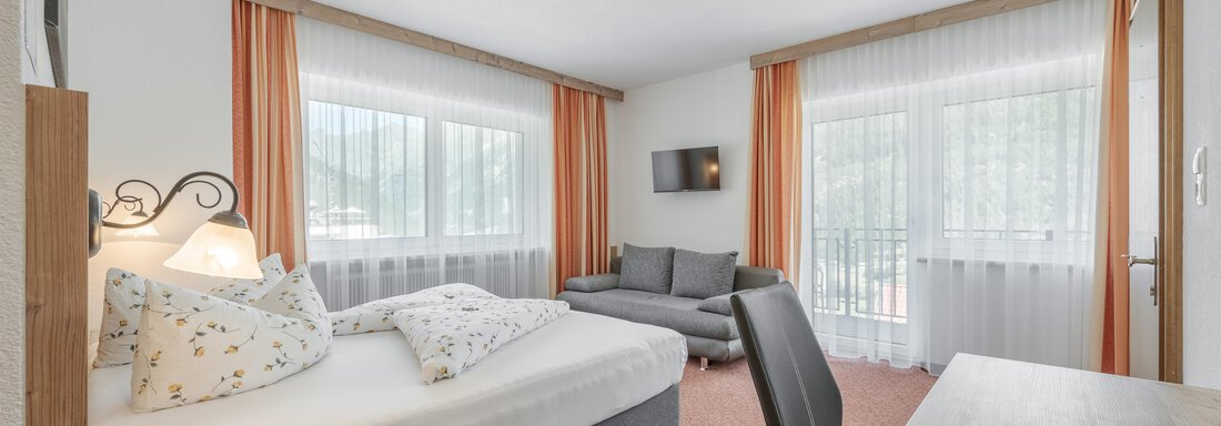 Schlafzimmer | © Stefanie Lohmann, Pension Charly (CC C) A cozy room with a double bed and a sofa.
Large windows provide plenty of daylight and a view outside. - Pension Charly - Sölden