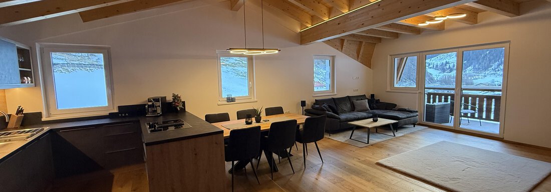 Modern apartment with wooden beam ceiling and large living area.  
Bright design with kitchen, dining table, and cozy couch. - Pension "Zur alten Mühle" - Sölden