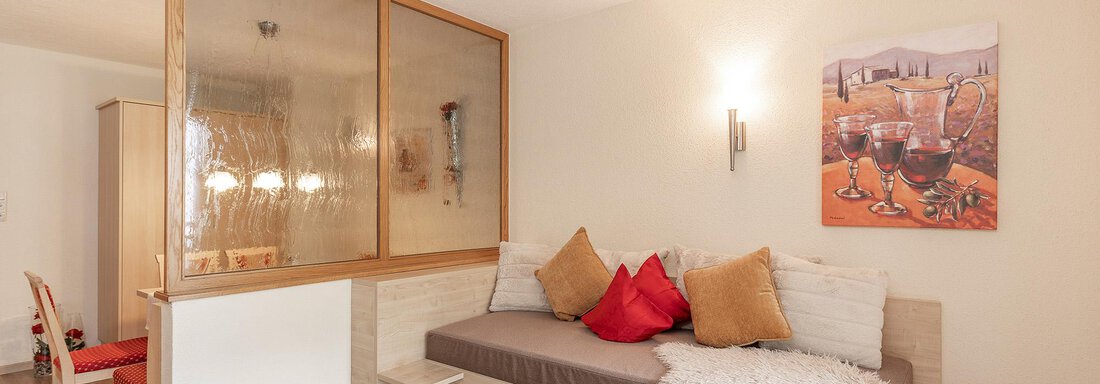An inviting living room with a cozy single bed that can also be used as a sitting couch. - Trofana Appartements - Sölden