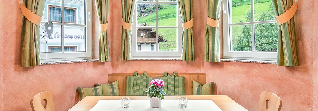 Ein gemütlicher Essbereich mit einem Holz-Tisch und bequemen Stühlen. Große Fenster bieten einen Blick auf die grüne Landschaft draußen. - Villa Castelbell - Sölden