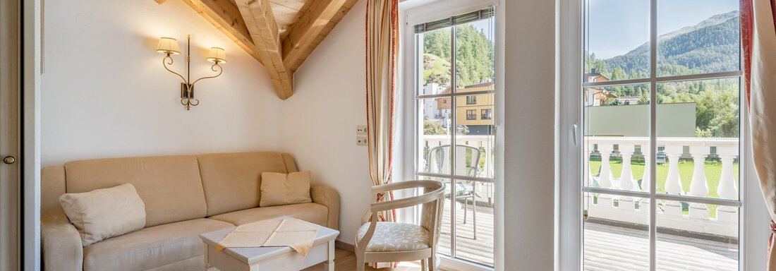 Ein gemütliches Wohnzimmer mit einem hellen Sofa und einem kleinen Tisch. Große Fenster bieten einen Ausblick auf die Natur. - Villa Castelbell - Sölden