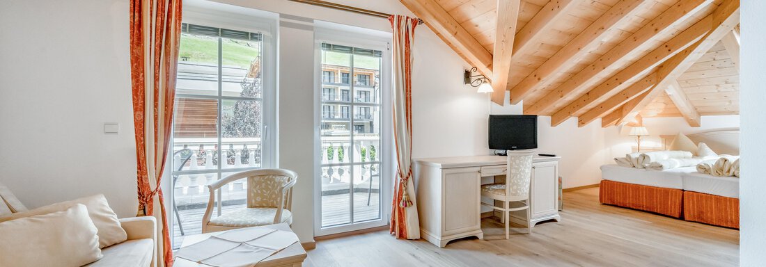 Ein helles Zimmer mit einer Holzdecke und großen Fenstern. Es gibt ein Sofa, einen Tisch und einen Fernseher. - Villa Castelbell - Sölden