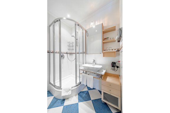 Ein modernes Badezimmer mit einer Duschkabine und einem Waschbecken. Der Boden ist mit blauen und weißen Fliesen gestaltet. - Villa Castelbell - Sölden