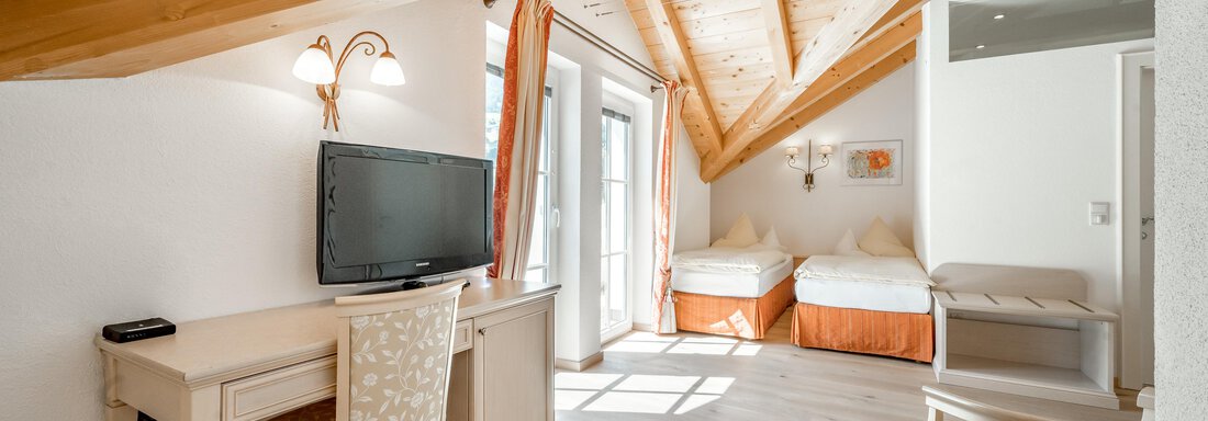 Ein gemütliches Schlafzimmer mit Holzdecke und großen Fenstern. Es gibt einen Schreibtisch, einen Fernseher und zwei Einzelbetten. - Villa Castelbell - Sölden