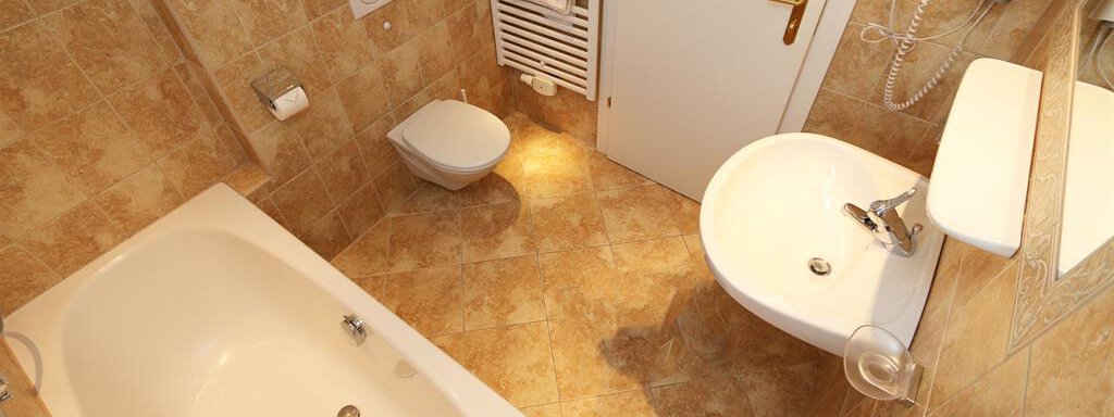 Ein modernes Badezimmer mit einer Badewanne, einem Waschbecken und einer Toilette. Die Wände sind in neutralen Farben und die Fliesen sind dekorativ. - Waldele - Sölden