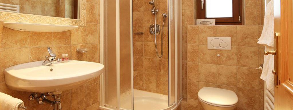 Ein modernes Badezimmer mit einer Dusche, einem Waschbecken und einem WC. Die Wände sind in warmen Farbtönen gehalten und es gibt große Spiegel. - Waldele - Sölden