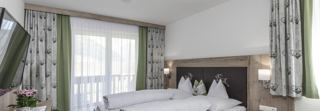 Ein modernes Hotelzimmer mit einem Doppelbett und einem gemütlichen Ambiente. Große Fenster sorgen für viel Tageslicht und einen Blick nach draußen. - Zenz´n Hof - Sölden