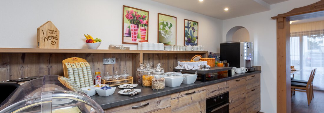 An inviting breakfast buffet with various foods and beverages. The wood look and decorative pictures create a cozy atmosphere. - Garni Stefani - Vent
