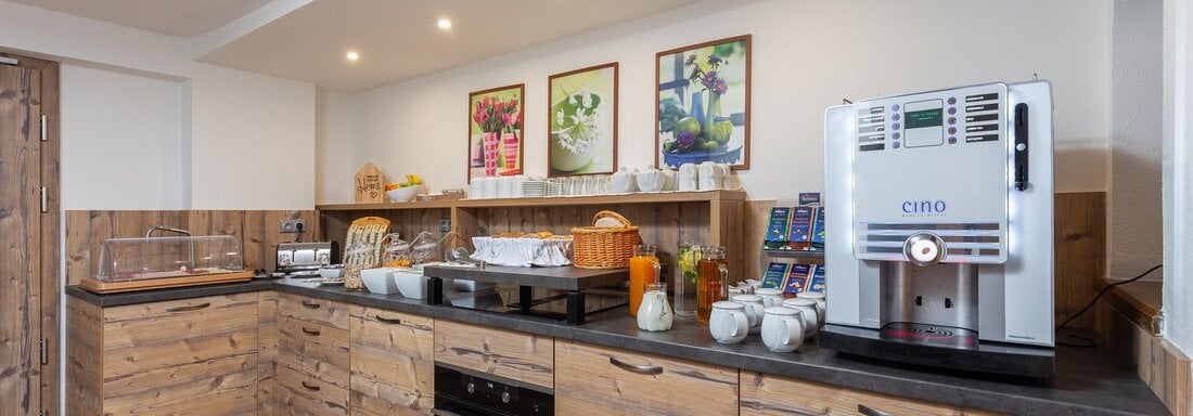 A modernly furnished wooden kitchen with elegant details. Various appliances and food items are ready on the countertop. - Garni Stefani - Vent
