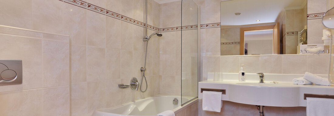 Ein modernes Badezimmer mit einer Badewanne und einer separaten Dusche. Die Wände sind hell gefliest und der Boden hat ein rotes und weißes Karomuster. - Hotel Vent - Vent
