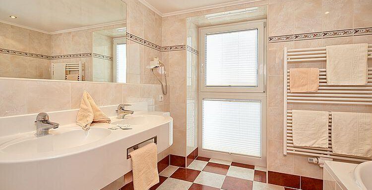 Ein modernes Badezimmer mit einer großen Waschtischanlage und einem Sichtfenster. Die Fliesen sind in einem klassischen Schwarz-Weiß-Rot-Muster gehalten. - Hotel Vent - Vent