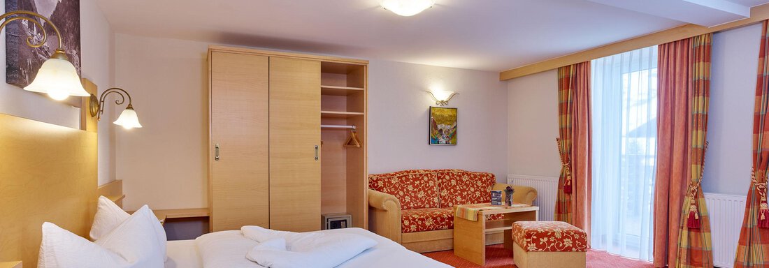 Ein gemütliches Hotelzimmer mit einem Doppelbett, einem Sofa und einem großen Fenster. Die Einrichtung ist modern und freundlich, mit warmen Farbtönen. - Hotel Vent - Vent