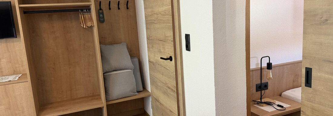 A modern room with a wood look and a small workspace. The furniture is simple and functional. - Mein Weisskugel - Vent