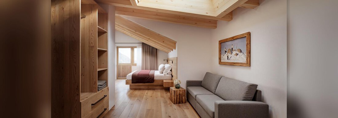 Ein modernes Zimmer mit Holzverkleidung und einem großen Dachfenster. Es gibt ein bequemes Sofa und ein Bett, umgeben von einem warmen, einladenden Design. - Chalet s’Tyrolia - Zwieselstein
