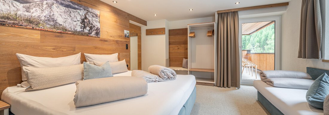 A modern bedroom with a large bed and a cozy sofa bed. The room has bright walls and plenty of daylight. - Garni Ötztal ROOMS & APARTS - Zwieselstein