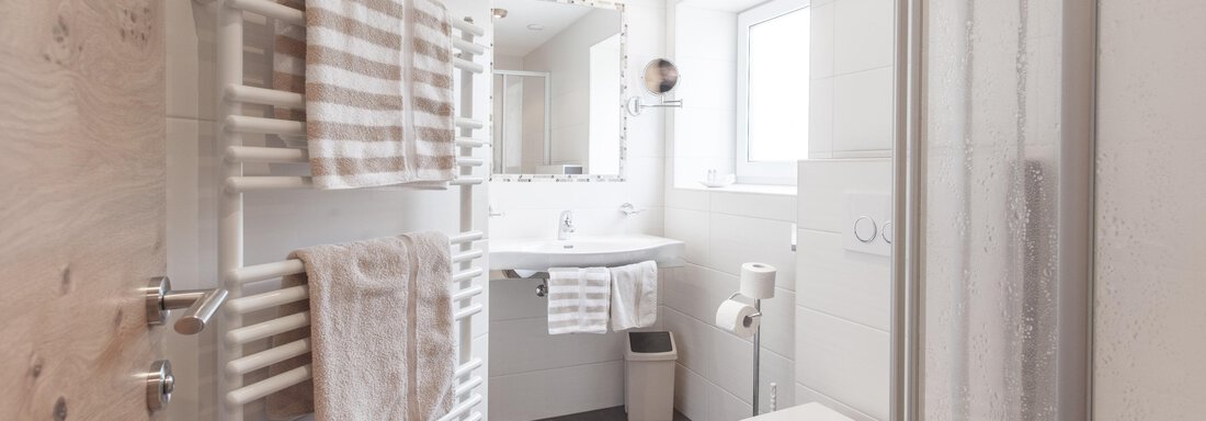 A modern bathroom with a shower, sink, and toilet. White walls and bright tiles create a friendly atmosphere. - Garni Ötztal ROOMS & APARTS - Zwieselstein