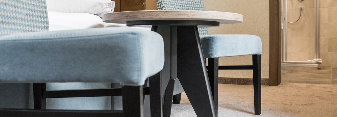 A modernly furnished room with a round table and two chairs. The colors are bright and friendly, and the carpet adds coziness. - Garni Ötztal ROOMS & APARTS - Zwieselstein
