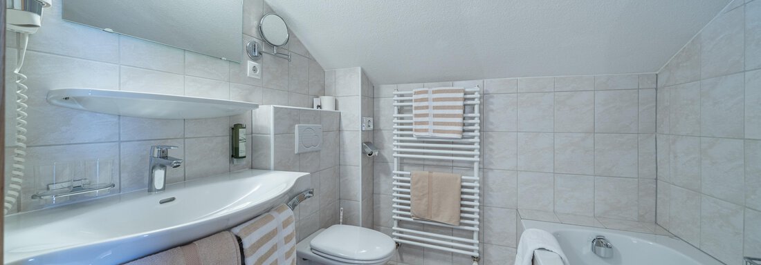 A modern bathroom with a bathtub and a sink. There are bright tiles and underfloor heating in a simple design. - Garni Ötztal ROOMS & APARTS - Zwieselstein